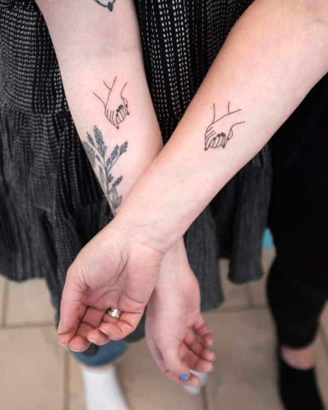Egymás kezét fogó tetoválás